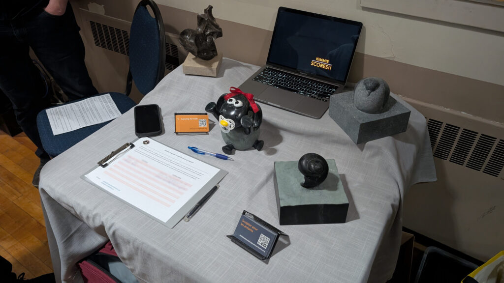 A small table with a laptop, business cards, and 4 small stone sculptures