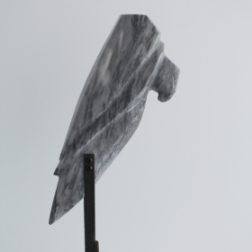 Rapace II_2 Grey marble sculpture shaped like a bird of prey's head, mounted on a tall black metal stand atop a white stone base.