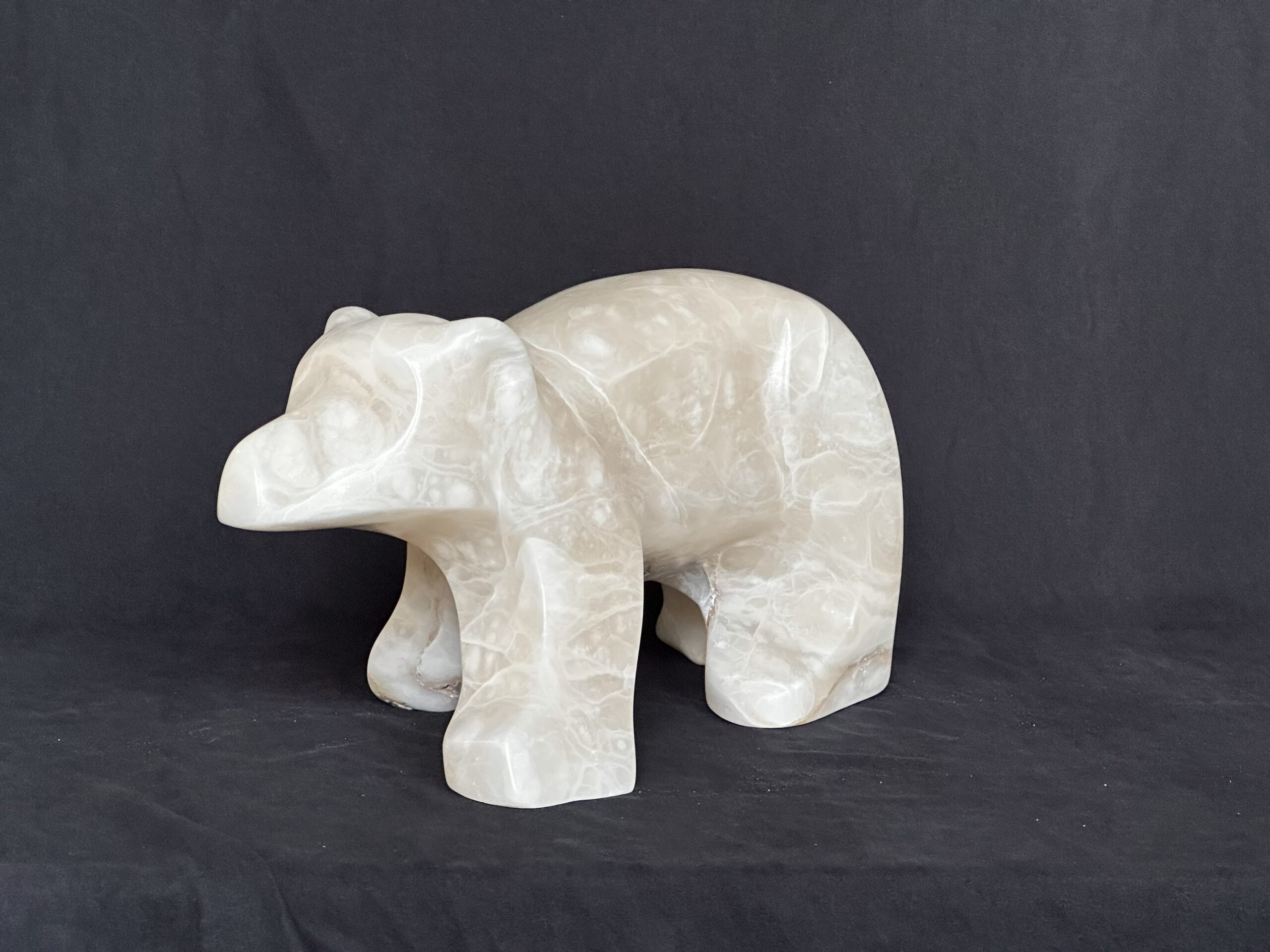Smooth off-white stone sculpture of a walking polar bear.