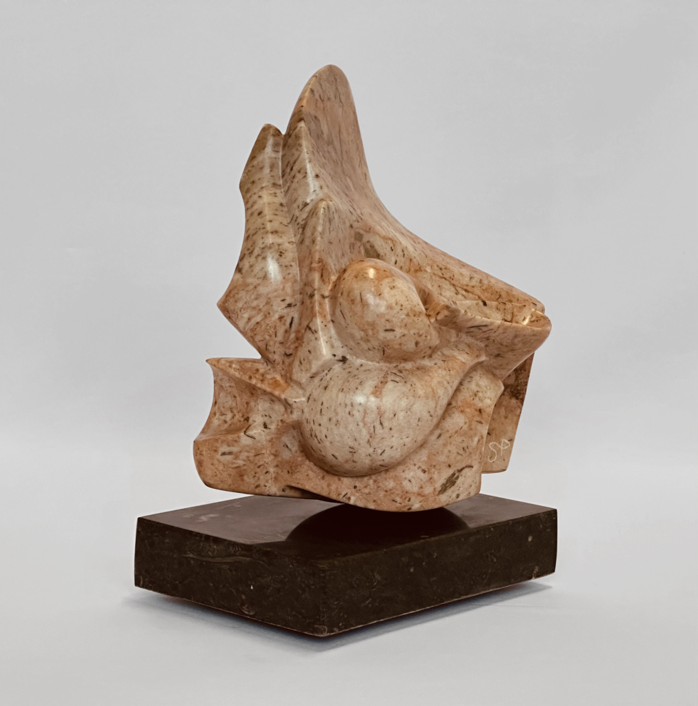 Sourire-de-lune_1.jpg Abstract sculpture in beige marbled stone with rounded, crescent-like lobes, set on a dark brown stone base.